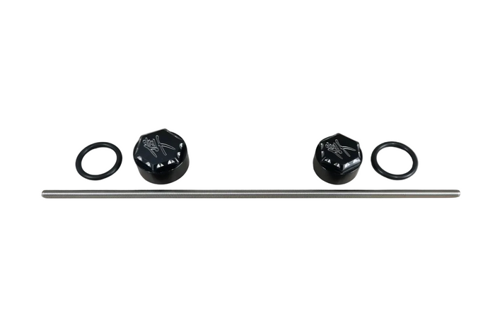 A metal rod with two black decorative end caps and two black O-rings laid out on a light wood surface.