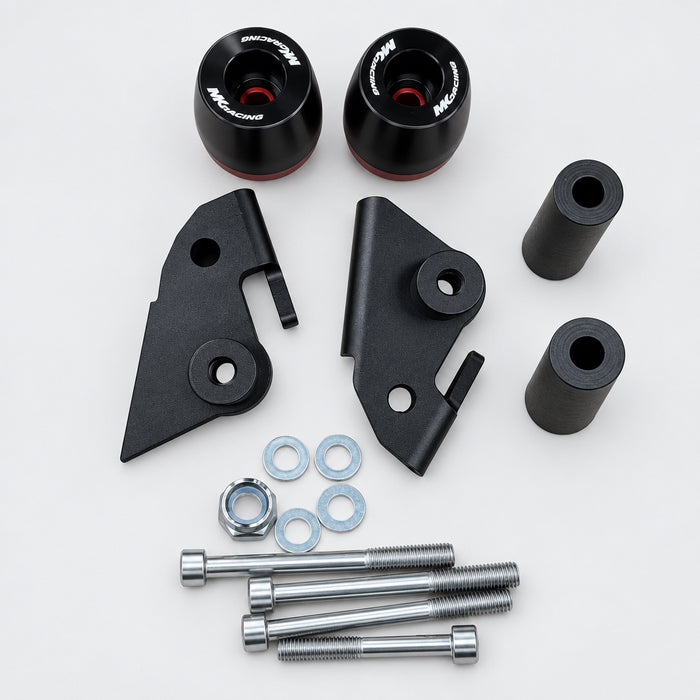 A set of black and silver motorcycle suspension or exhaust components laid out on a light wood surface, including two black cylindrical canisters, two black bracket pieces, two black cylindrical tubes, several silver bolts, washers, and nuts.