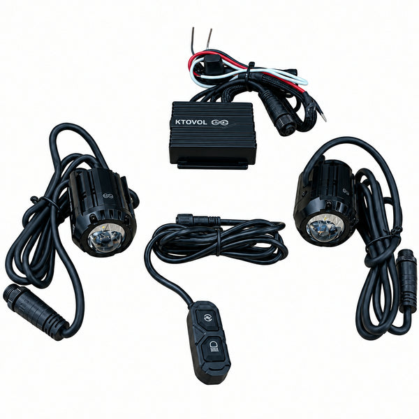 A set of black car-mounted LED light modules with wiring, a small black controller box, and a remote switch, arranged on a light wood tabletop.
