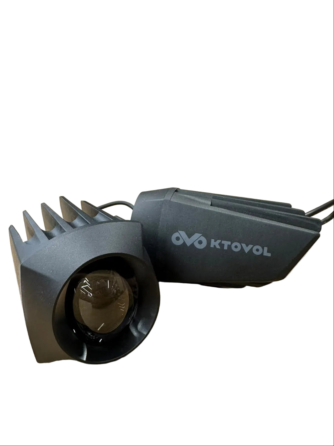 A black KTOVOL LED light fixture with a ribbed housing and a clear lens, resting on a wooden table in a retail store setting with a person blurred in the background.