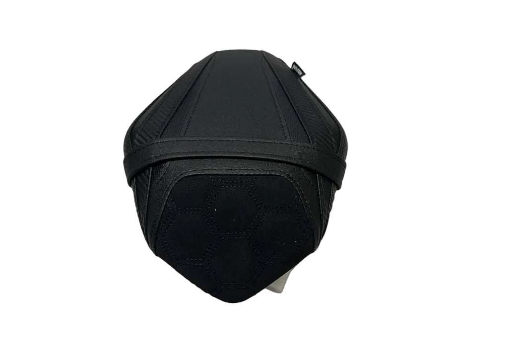 A black motorcycle or scooter seat cover/pad shown from the front, resting on a white protective sheet in what appears to be a warehouse or storage area.