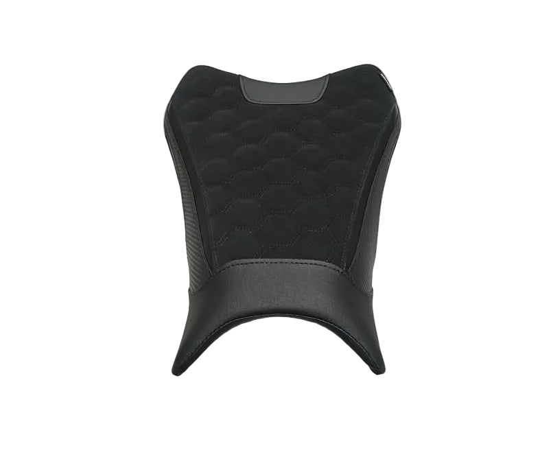 A black motorcycle or scooter seat cover or cushion with a quilted honeycomb pattern and smooth lower section, displayed on a white sheet in a warehouse aisle with cardboard boxes on both sides.