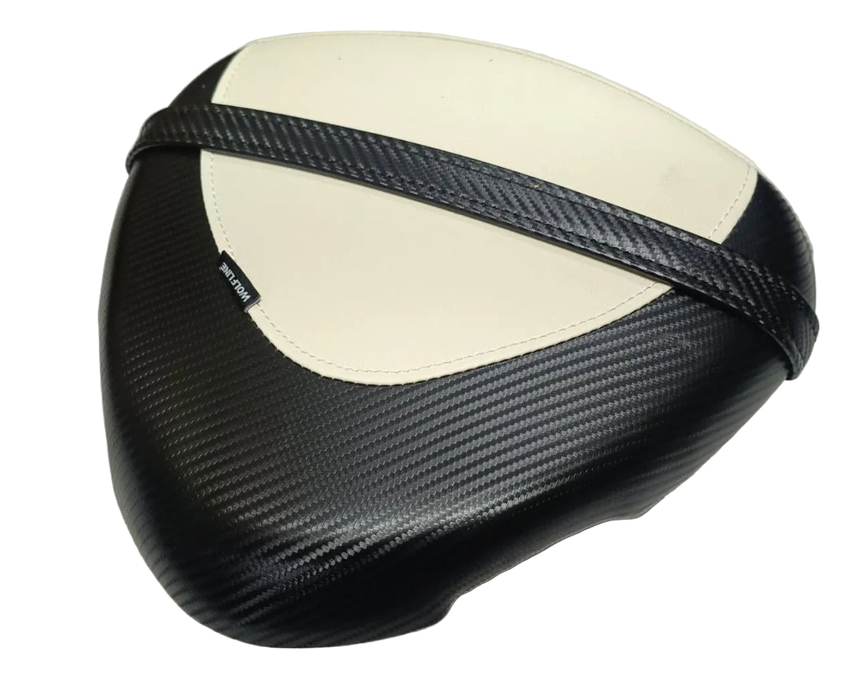 A motorcycle or scooter seat cover featuring a black carbon fiber weave pattern with a contrasting cream-colored center panel and a black strap detail, shown on a light-colored fabric surface.