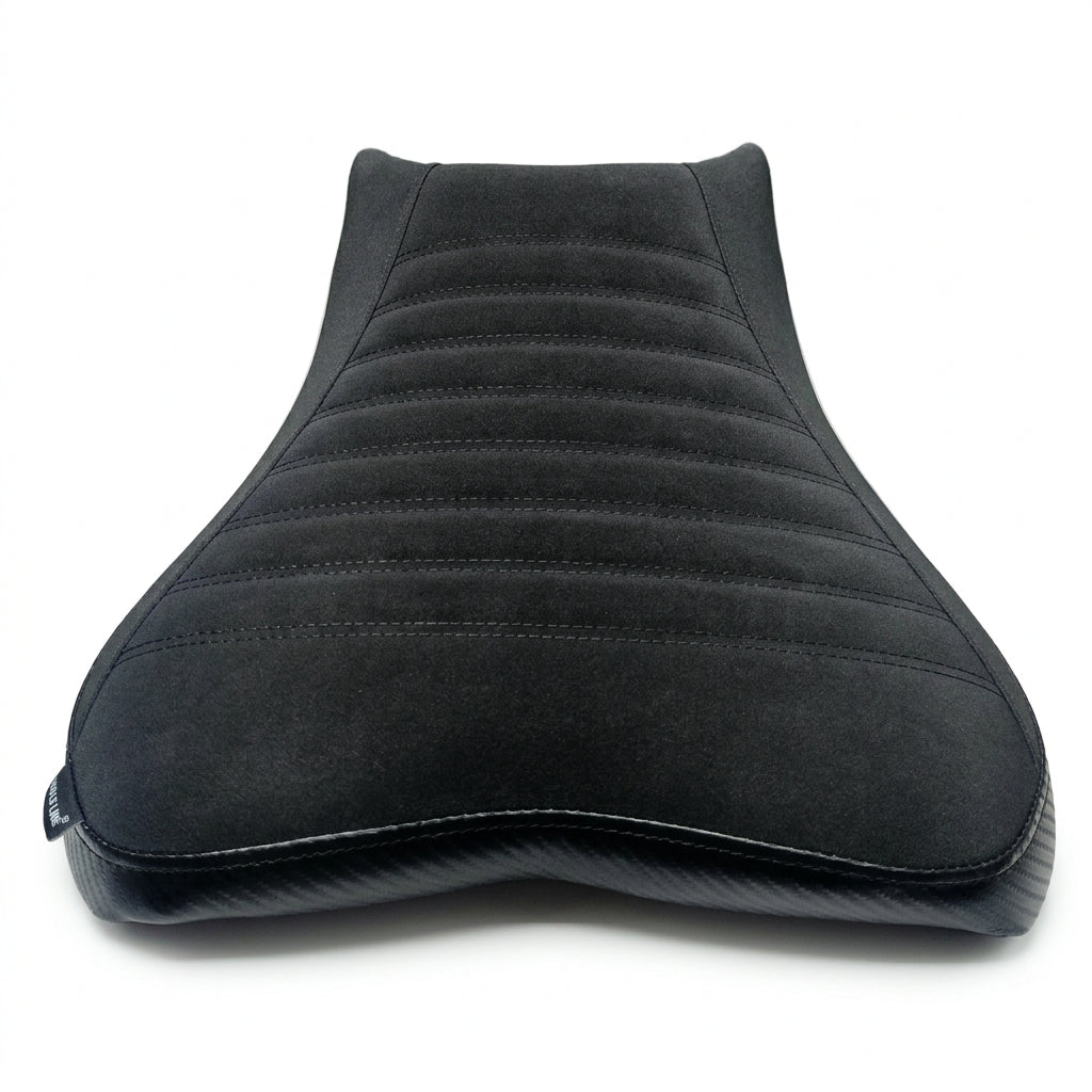 A black motorcycle or scooter seat cover with horizontal channel stitching, shown resting on a white sheet.