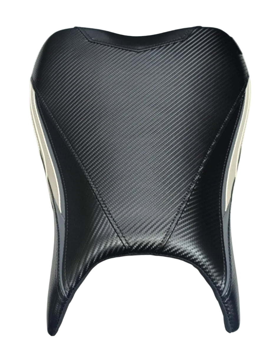 A motorcycle or scooter seat cover with a black carbon-fiber textured pattern, shown on a white surface with parts of a person's legs and feet visible in the background.