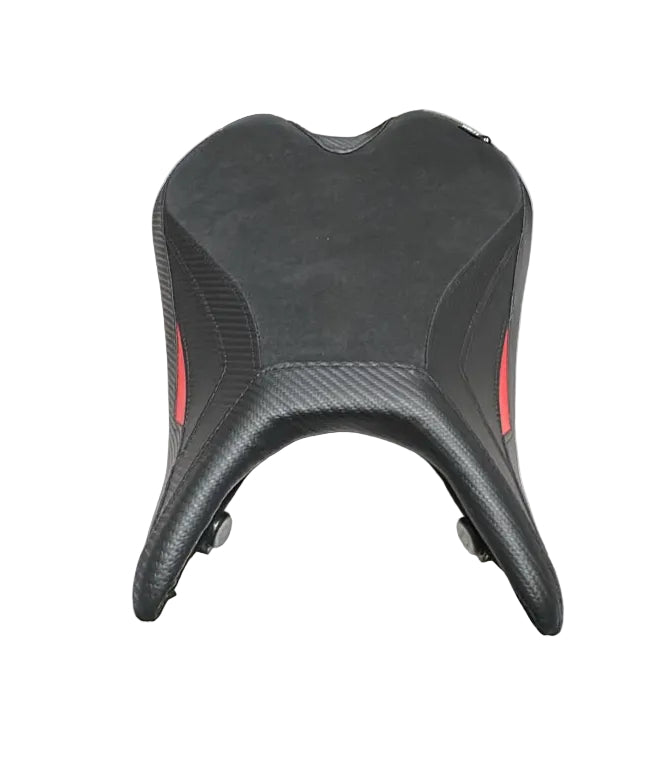 A black motorcycle or scooter seat with red side accents, displayed on a white sheet on a table inside what looks like a warehouse or shop.
