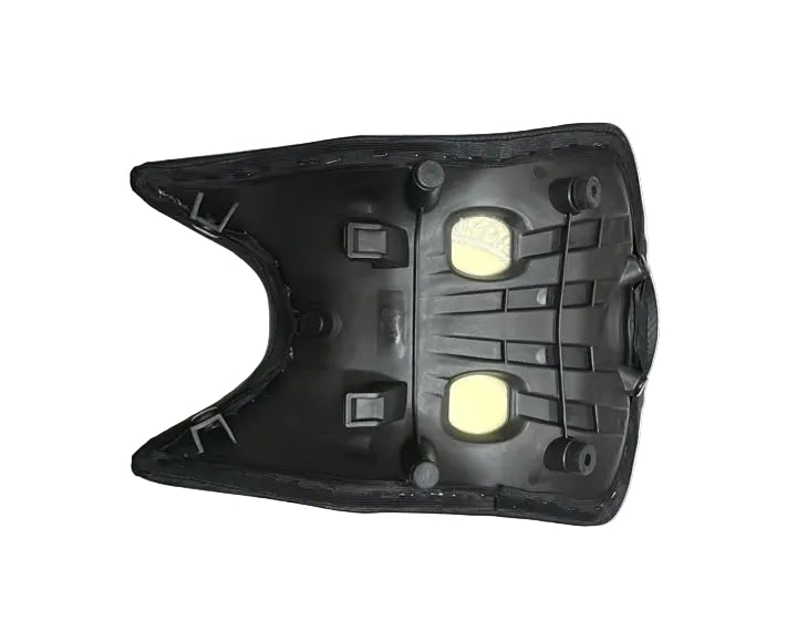 A black molded plastic replacement part, likely a seat cushion backing or support panel, displayed on a white protective sheet over stacked cardboard boxes.