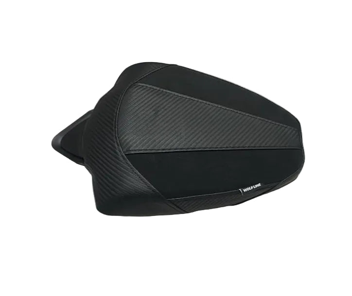 A black motorcycle or scooter seat cover with a textured carbon-fiber pattern, resting on a white protective plastic sheet in a warehouse setting.