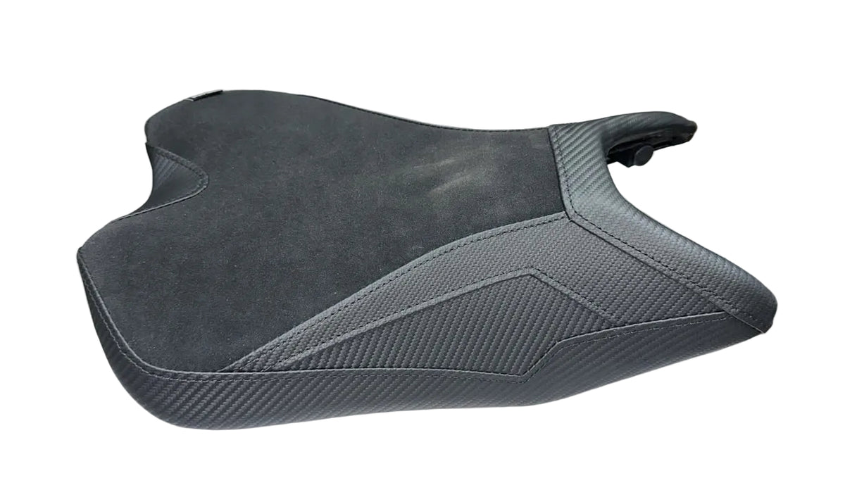 A dark gray motorcycle or scooter seat cover featuring a combination of suede-like texture and a carbon fiber weave pattern, shown on a plain white background.
