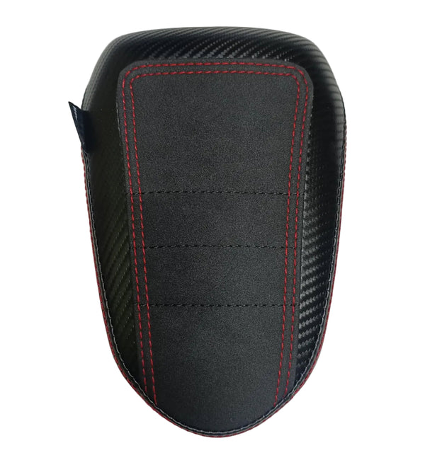 A black motorcycle or scooter seat cover featuring a carbon fiber pattern on the sides and a central black panel with red contrast stitching, shown on a light gray textured background.