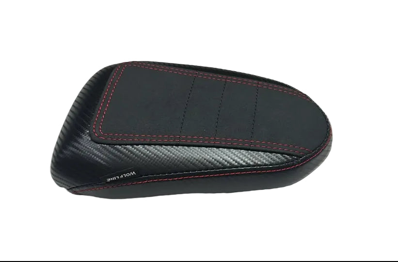 A black motorcycle or scooter seat backrest cover with red contrast stitching and a carbon fiber pattern, resting on a white plastic sheet.