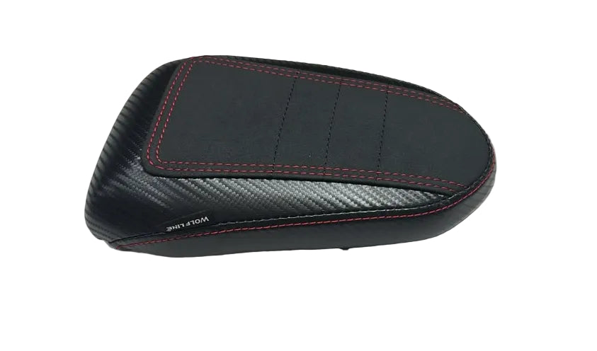 A black motorcycle or scooter seat backrest cover with red contrast stitching and a carbon fiber pattern, resting on a white plastic sheet.